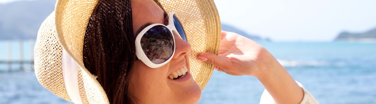 Woman in sun hat with sunglasses on beach