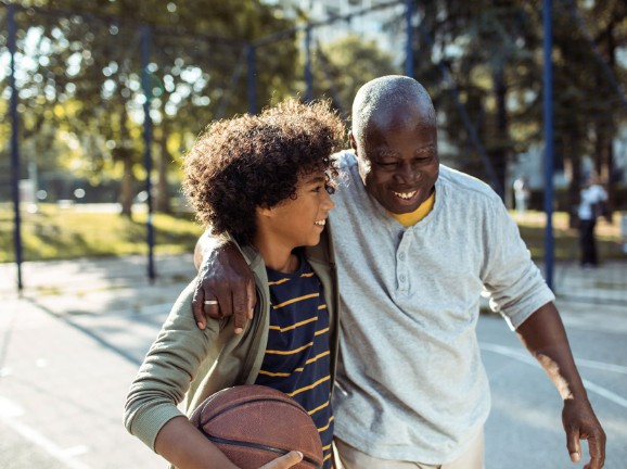 Grandfather and grandson playing basketball outside and hugging