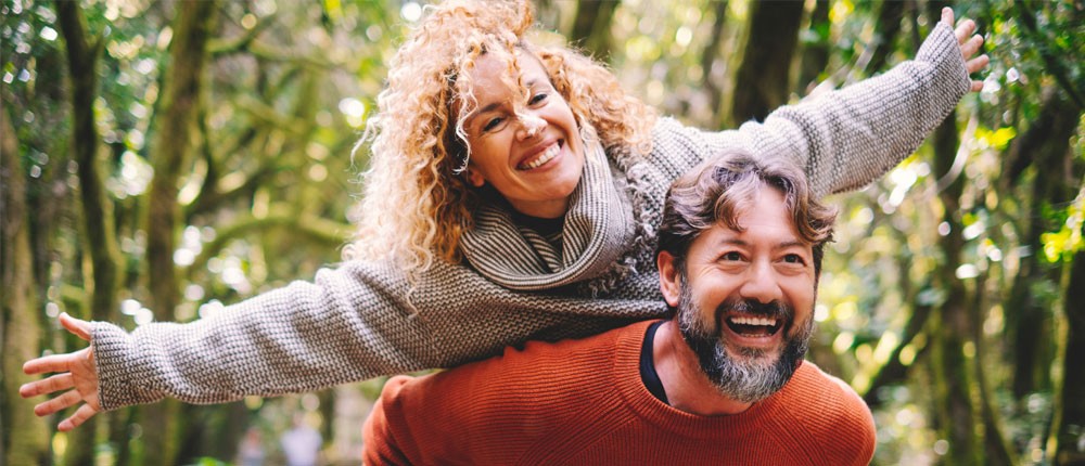 Mature woman with arms outstretched on back of man